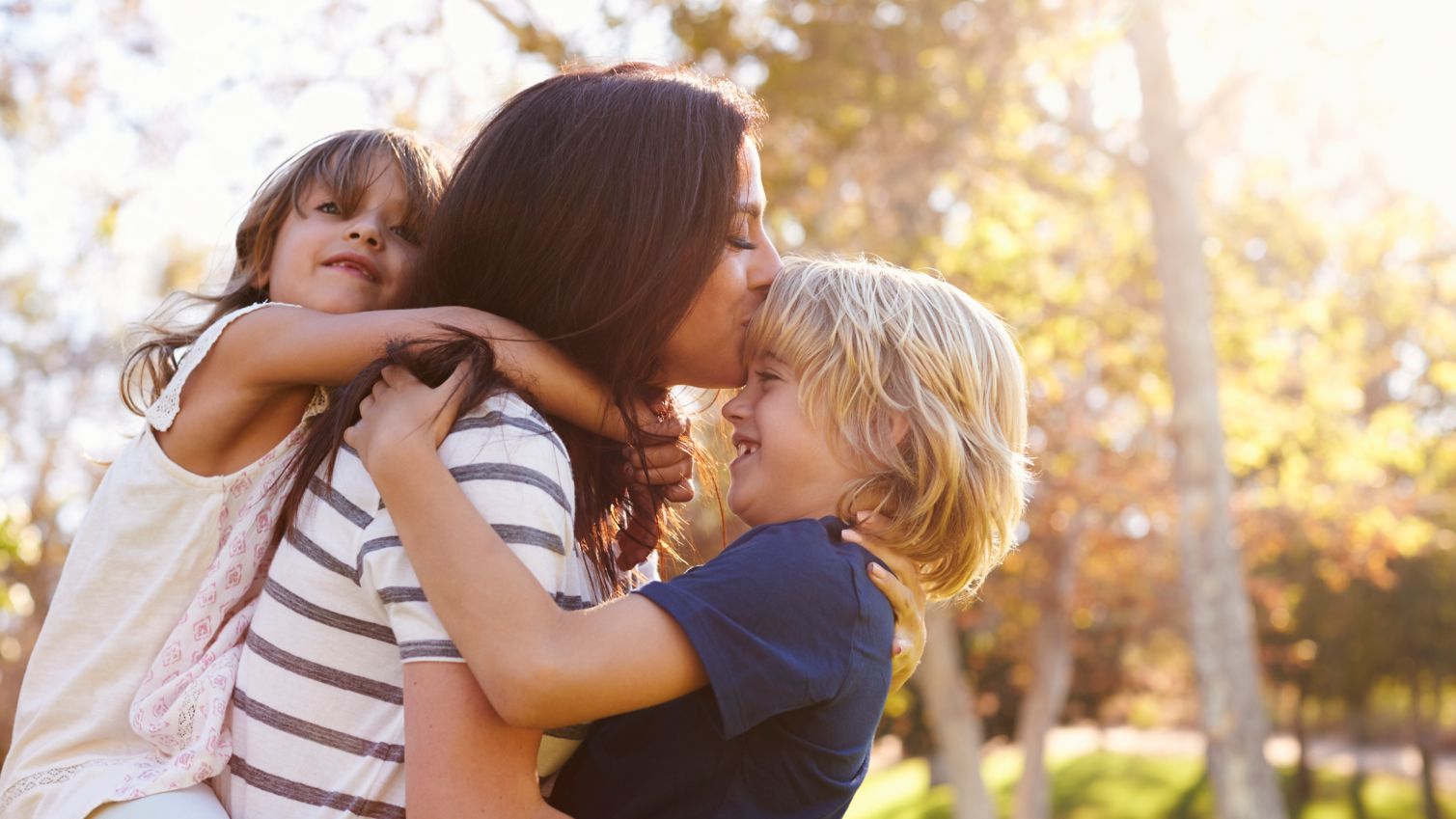 Mom holds son and daughter outside